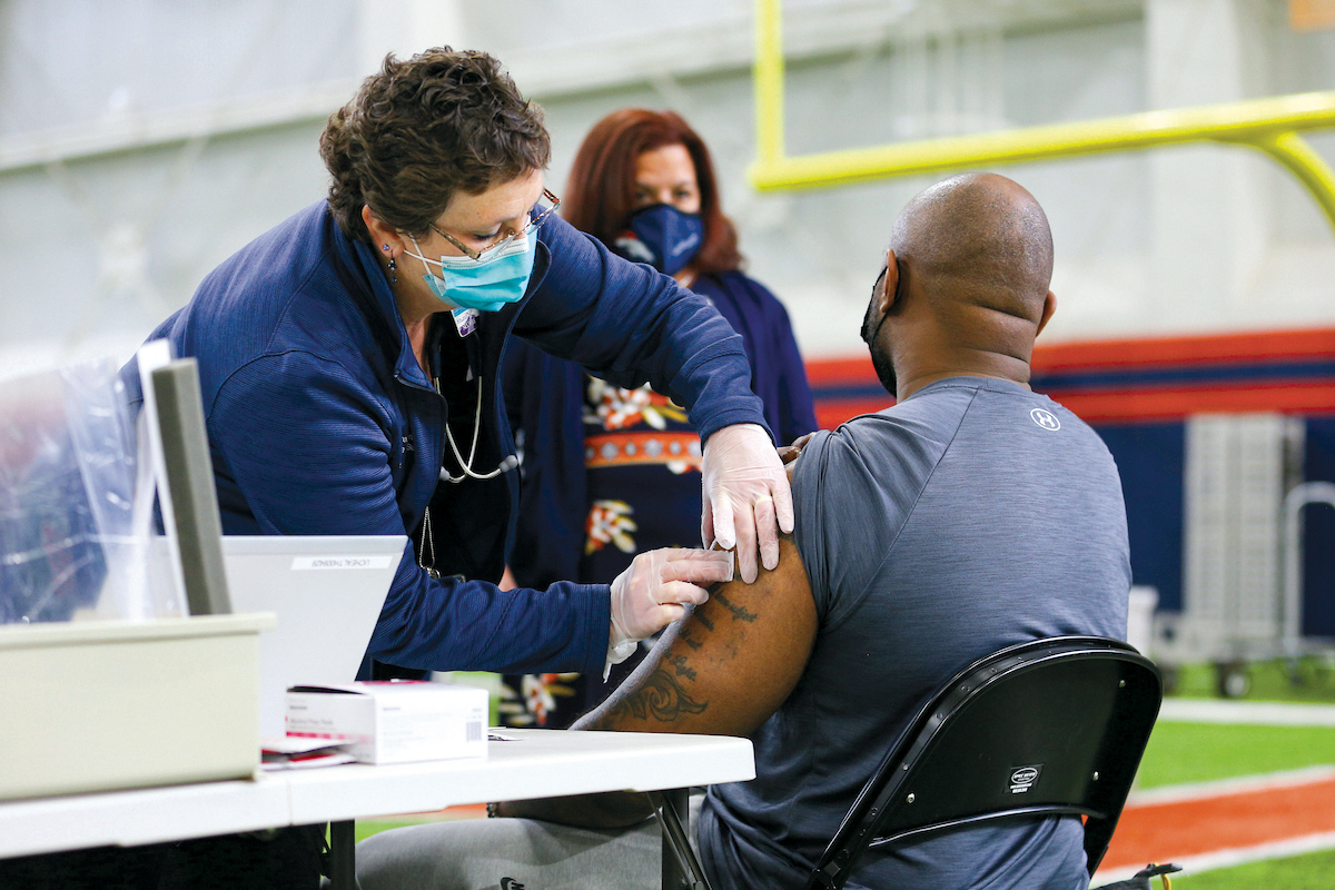 Barron (in background) oversees vaccination event for the Denver