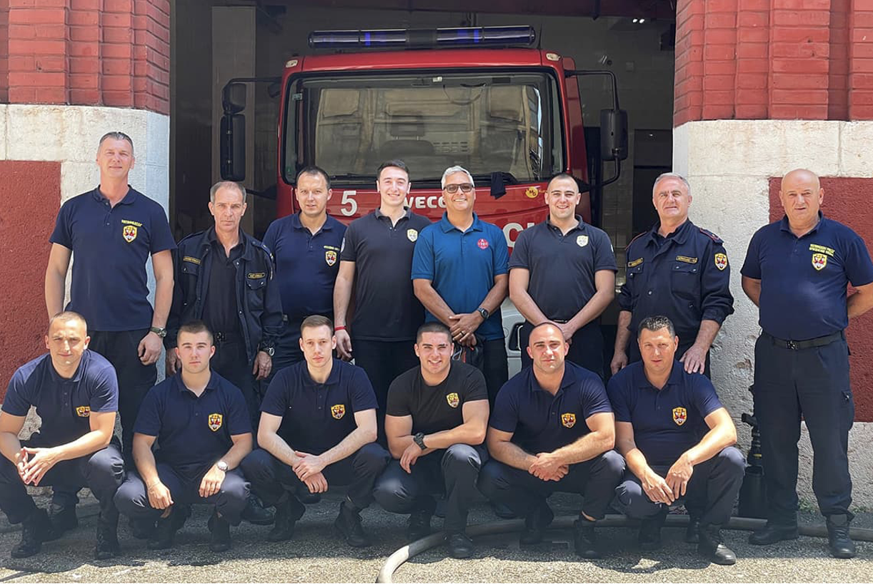 Chris VanDjik stands in front of a firestation with firefighters from Zadar, Croatia